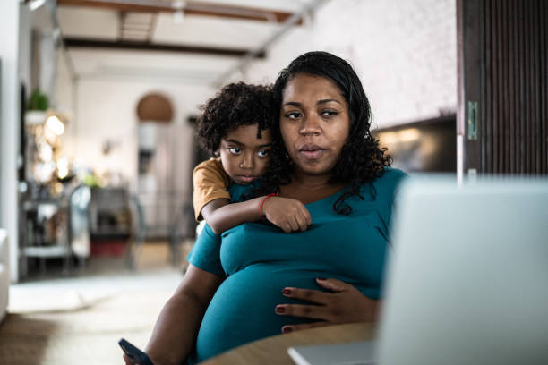 Pregnant woman using laptop at home with son