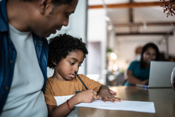 istock Father helping son drawing/writing at home 1390902223