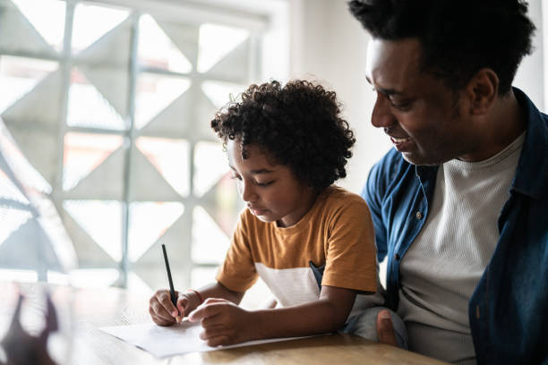istock Father helping son drawing/writing at home 1390902739