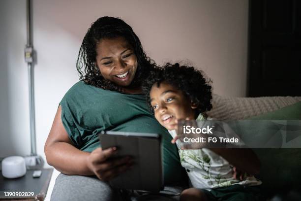Mother and son using digital tablet lying on the bed at home
