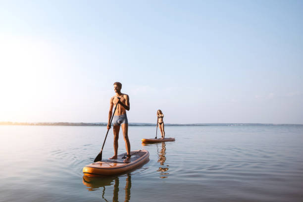 young people traveling along the river on sap boards - paddle surfing stockfoto's en -beelden
