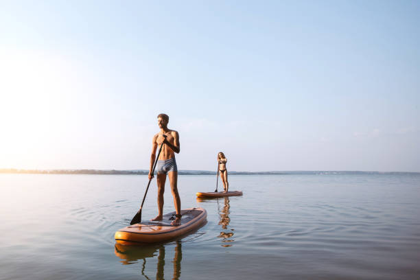 young people traveling along the river on sap boards - paddle surfing stok fotoğraflar ve resimler