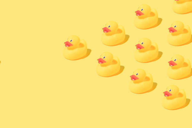 istock Pattern made of rubber bath ducks on yellow background. Copy space. 1390903068