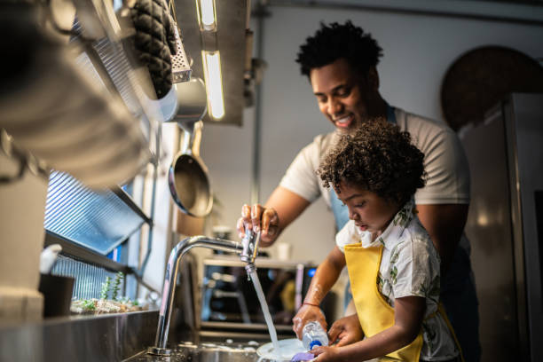istock Father and son washing dishes at home 1390903153