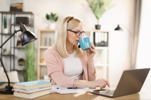 istock Female freelancer sitting at table and typing on laptop while drinking coffee 1390903279