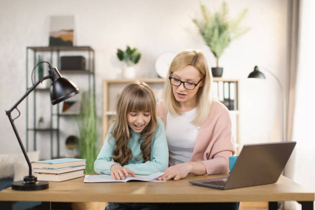 istock Parent mom teaching school child distance learning online virtual class on computer. 1390903352