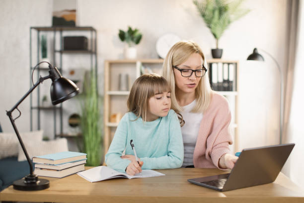 istock Parent or tutor helping child daughter with remote education 1390903364