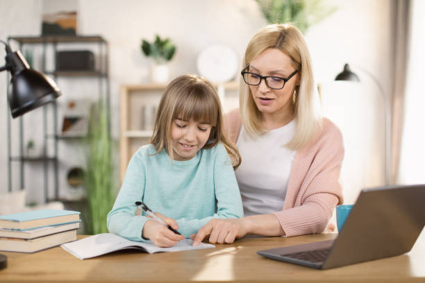 istock Caucasian tutor engaged with schoolgirl help complete tasks sitting at table at home. 1390903391