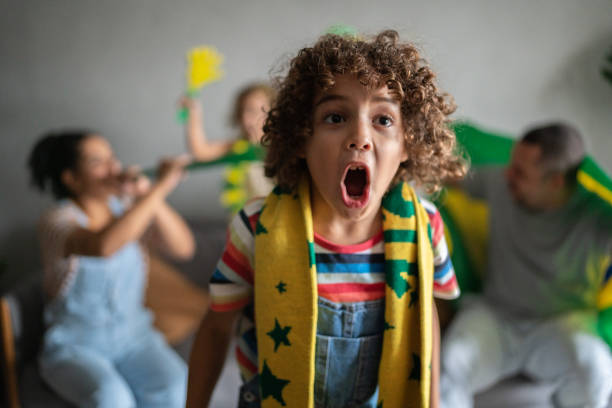 ragazzo che tifa per la squadra brasiliana con la famiglia a casa - little boys people indoors soccer foto e immagini stock