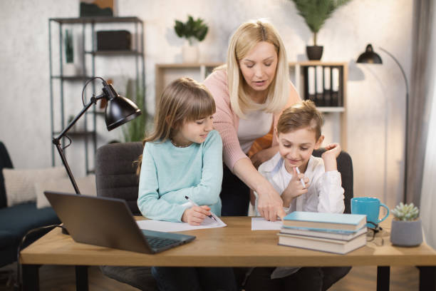 istock Caucasian young woman help her son do homework with daughter using laptop 1390903629