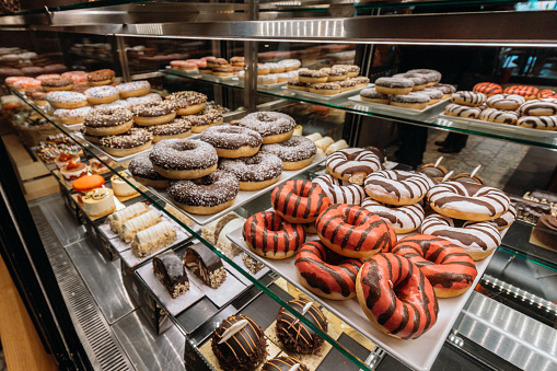 view of many assorted donuts on a bakery counter, colorful donuts
