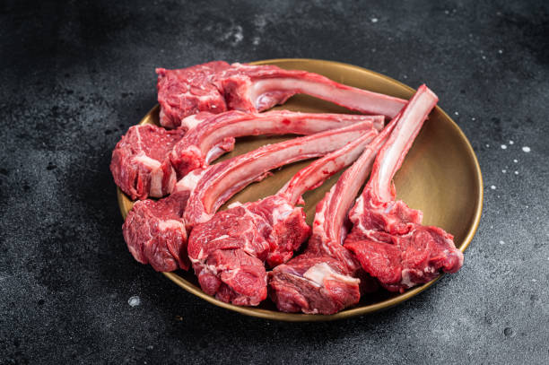 steak de côtelette d’agneau, escalope de viande de mouton crue dans une assiette dorée. fond noir. vue de dessus - rack of lamb chop raw meat photos et images de collection