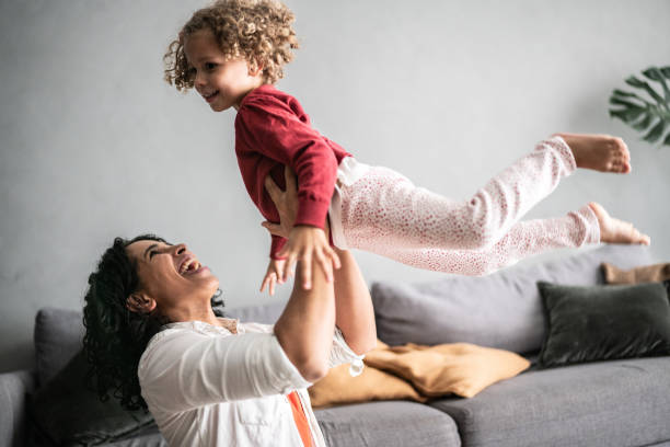 istock Mother playing flying with daughter at home 1390904825