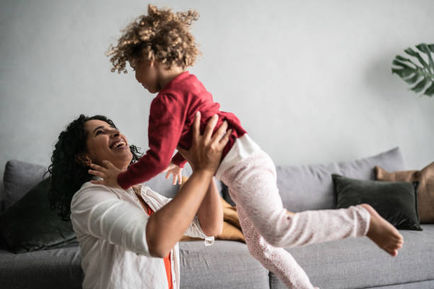 istock Mother playing flying with daughter at home 1390904828
