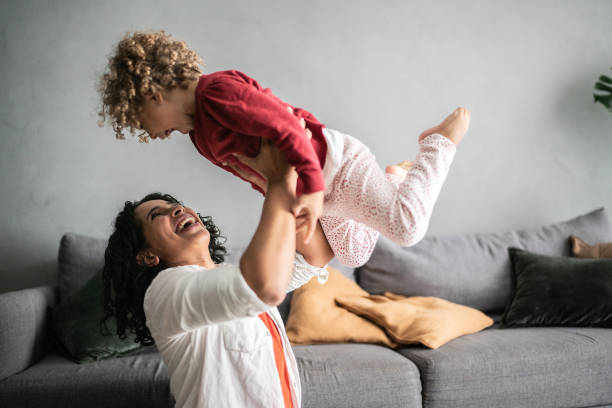 istock Mother playing flying with daughter at home 1390904860