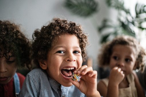 Boy eating brigadeiro with siblings at home