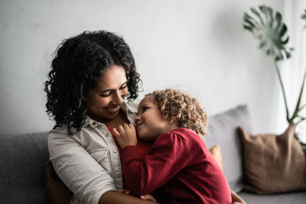 istock Daughter sitting on mother's lap at home 1390905007