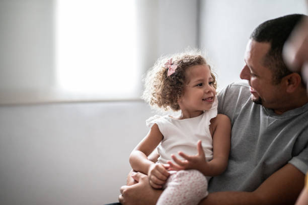 istock Daughter sitting on father's lap at home 1390905078