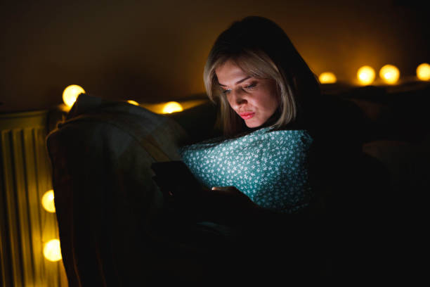 istock Woman lounging on the sofa late at night, using smart phone for fun 1390905942