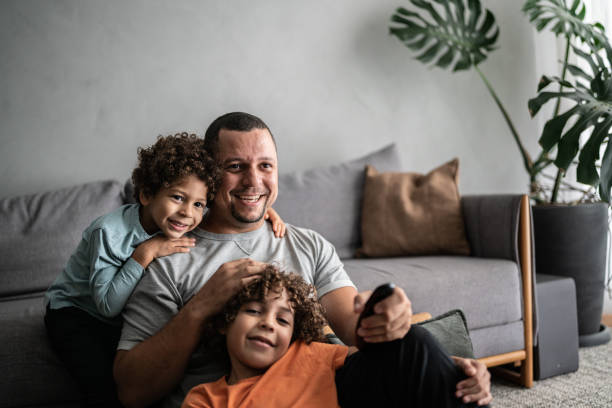 père et fils regardant la télévision à la maison - zapping photos et images de collection