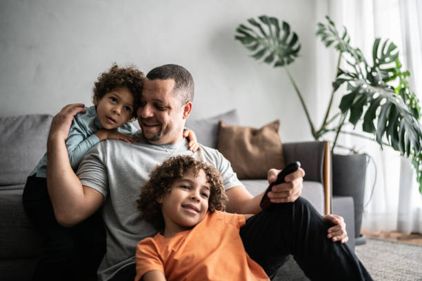 padre e hijos viendo la televisión en casa - son love father childhood fotografías e imágenes de stock