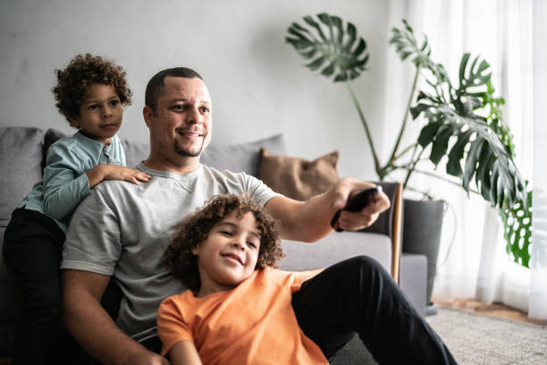 istock Father and sons watching TV at home 1390905980