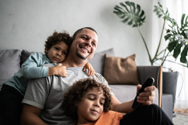 istock Father and sons watching TV at home 1390905983