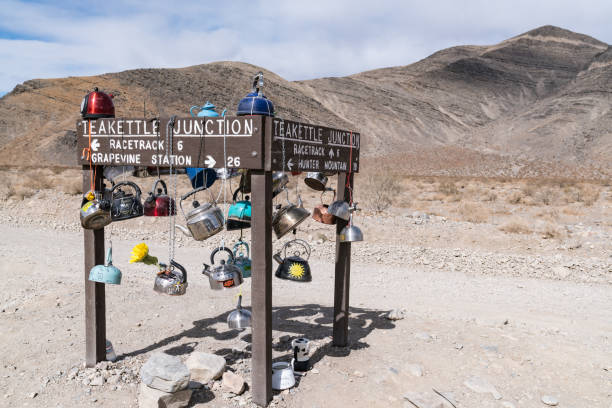 Teakettle Junction along the road to the Racetrack Playa Teakettle Junction, CA - March 5, 2022: Teapots hang from the directional sign at Teakettle Junction.  This is part of a tradition where travelers hang teapots as they pass through. teakettle junction stock pictures, royalty-free photos & images