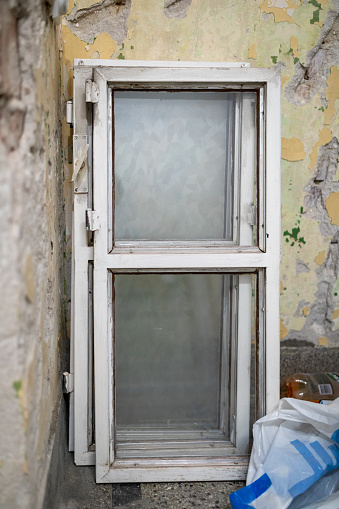 White wooden window frames with glass inside of old ruined apartment