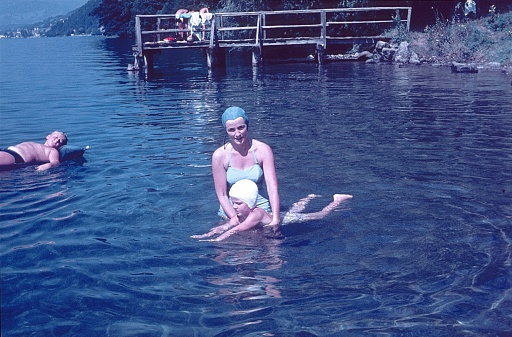 Bavaria, Germany, 1964. A mother practices swimming movements with her daughter in a lake. Also Noch: the son, lying on an air mattress.
