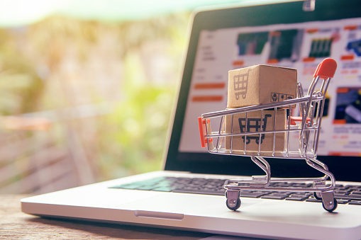 Shopping online concept - Parcel or Paper cartons with a shopping cart logo in a trolley on a laptop keyboard. Shopping service on The online web. offers home delivery.