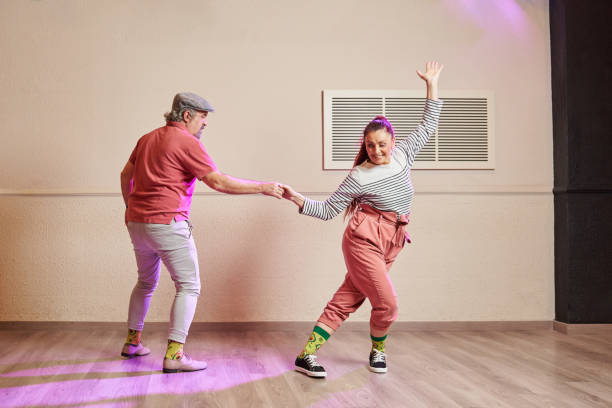 un couple de danseurs de lindy hop seniors portant des chaussettes amusantes - couple mature adult senior adult 40s photos et images de collection