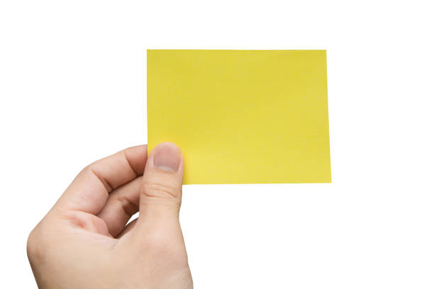 istock Hand holding yellow paper isolated on white 1390910613