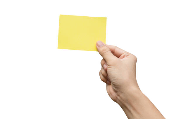 istock Hand holding yellow paper isolated on white 1390910667