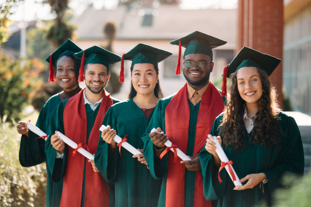istock Portrait of happy graduating classmates with certificates looking at camera. 1390915434