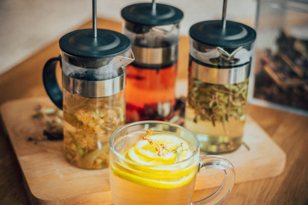 boisson chaude saine et relaxante avec un mélange de tilleul, sauge, tranche de citron, thé vert, thym, grande variété de feuilles et de fleurs de thé séchées multicolores sur la table, tisanes - chamomile plant photos et images de collection