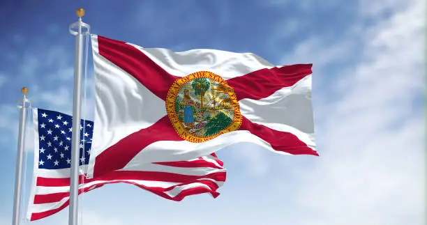 Photo of The Florida state flag waving along with the national flag of the United States of America