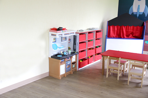 Playroom for children in a house with toys such as a kitchen, a table, a puppet theater, a ball pool, a piano and wooden tools for the little ones to play and learn