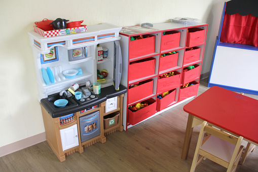 Playroom for children in a house with toys such as a kitchen, a table, a puppet theater, a ball pool, a piano and wooden tools for the little ones to play and learn