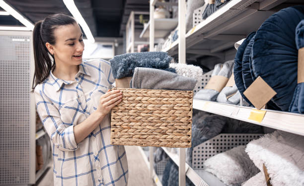 una joven con una cesta de mimbre llena de mantas en una tienda de mejoras para el hogar. - wicker basket store gift shop fotografías e imágenes de stock