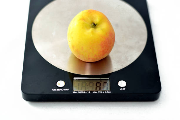 istock Weighing an Apple fruit on a digital kitchen scale in grams isolated on white background, healthy food, weight loss concept 1390924651