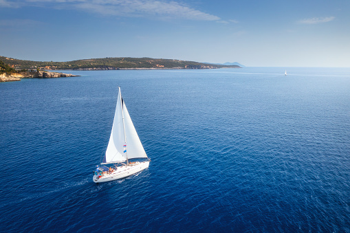 Aerial view of beautiful yacht. Boat on the sea at sunset in summer. Lefkada island, Greece. Top view of luxury yachts, sailboats, clear blue water, sky, mountain. Travel. Cruise vacation. Yachting