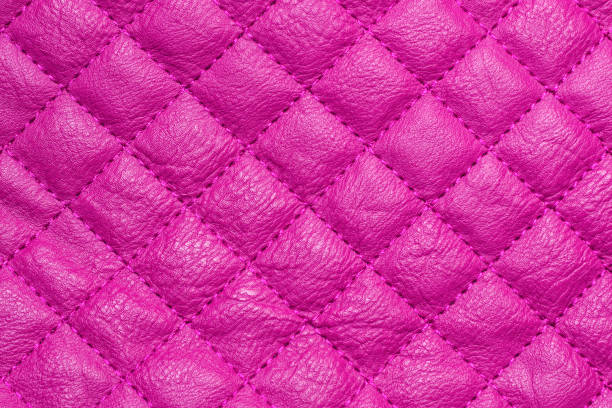 istock Quilted fabric texture. The repetitive pattern of leather with pink diamond stitching 1390927688