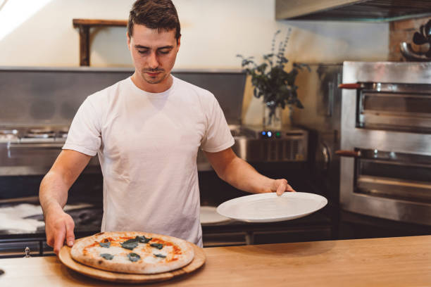 istock Chef serving pizza on a wooden board 1390928808