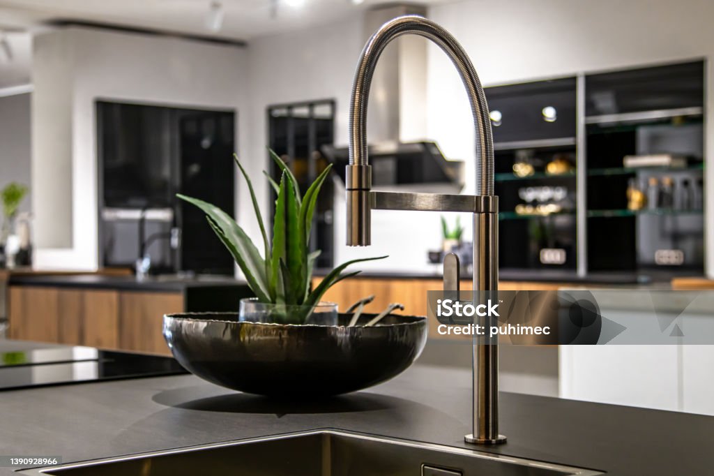 New modern steel faucet and kitchen room sink close up. Steel faucet in a stylish modern kitchen. Minimalism in refurbished apartment. Design Stock Photo