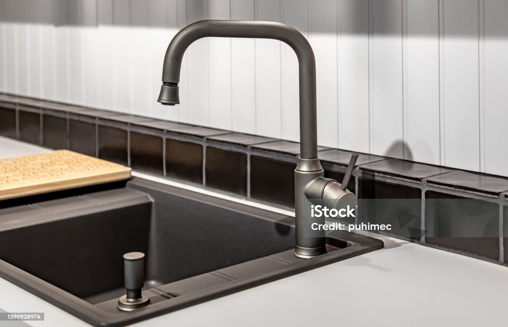 Steel faucet in the kitchen in the interior. Steel faucet close-up in the interior of a modern kitchen. Appliance Stock Photo