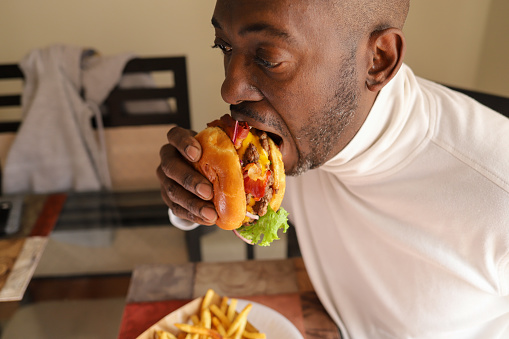 A portrait of a black African-American man eating a hamburger