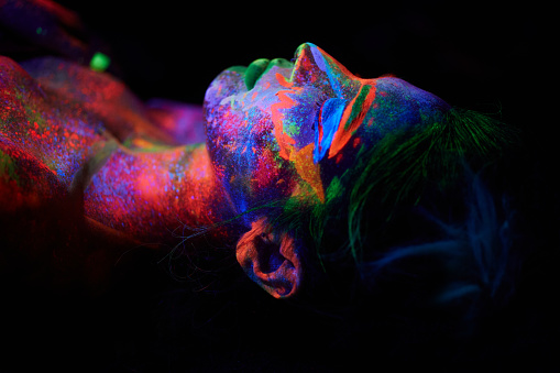 portrait of young girl under ultraviolet light neon makeup on her face