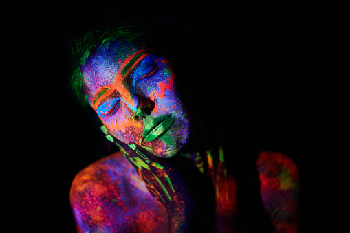 portrait of young girl under ultraviolet light neon makeup on her face