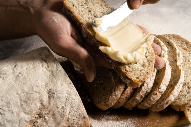 Male hands spread butter on a slice of bread.